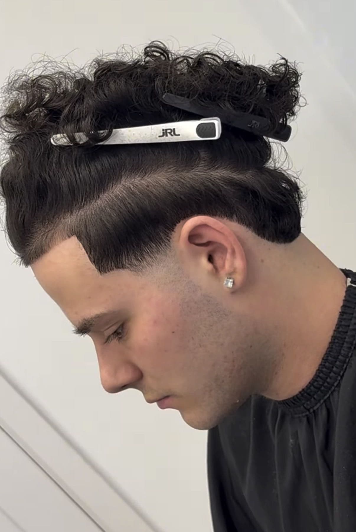 Curly hair sectioned with a clip, taper at the side, by Fin
