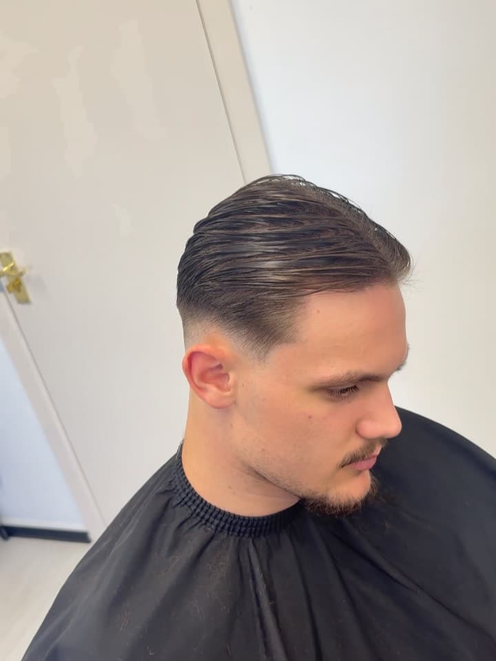 Slicked back style with a skin fade, by Fin