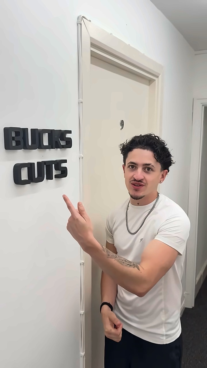 Bucks at the studio door, with the black Bucks Cuts lettering on the wall beside it